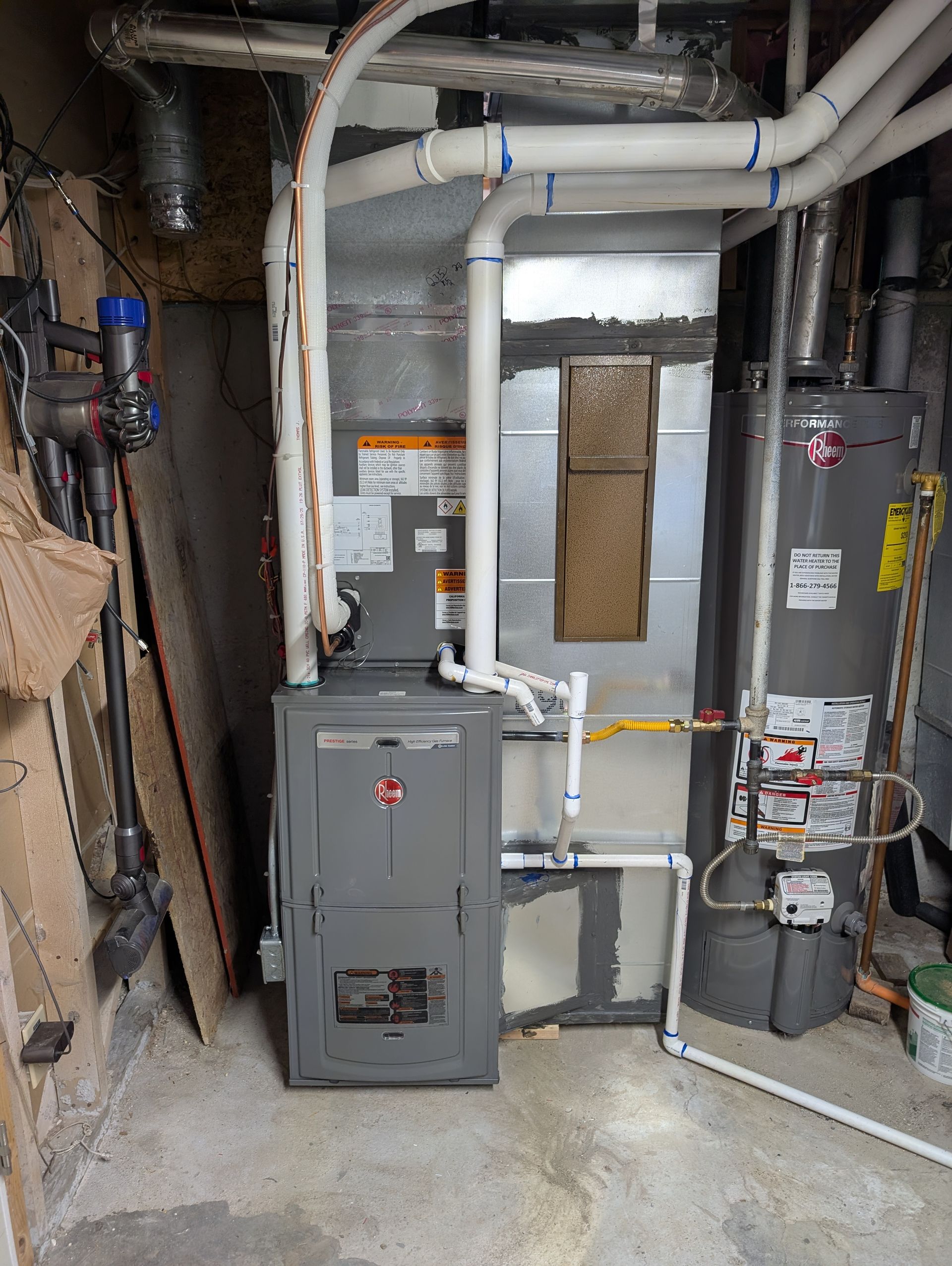 Basement utility area with furnace, water heater, and exposed pipes and ductwork