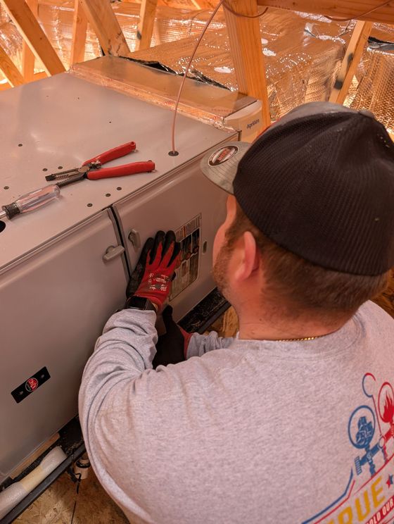 Worker installing panels inside an attic, using red gloves and tools on a metal surface.