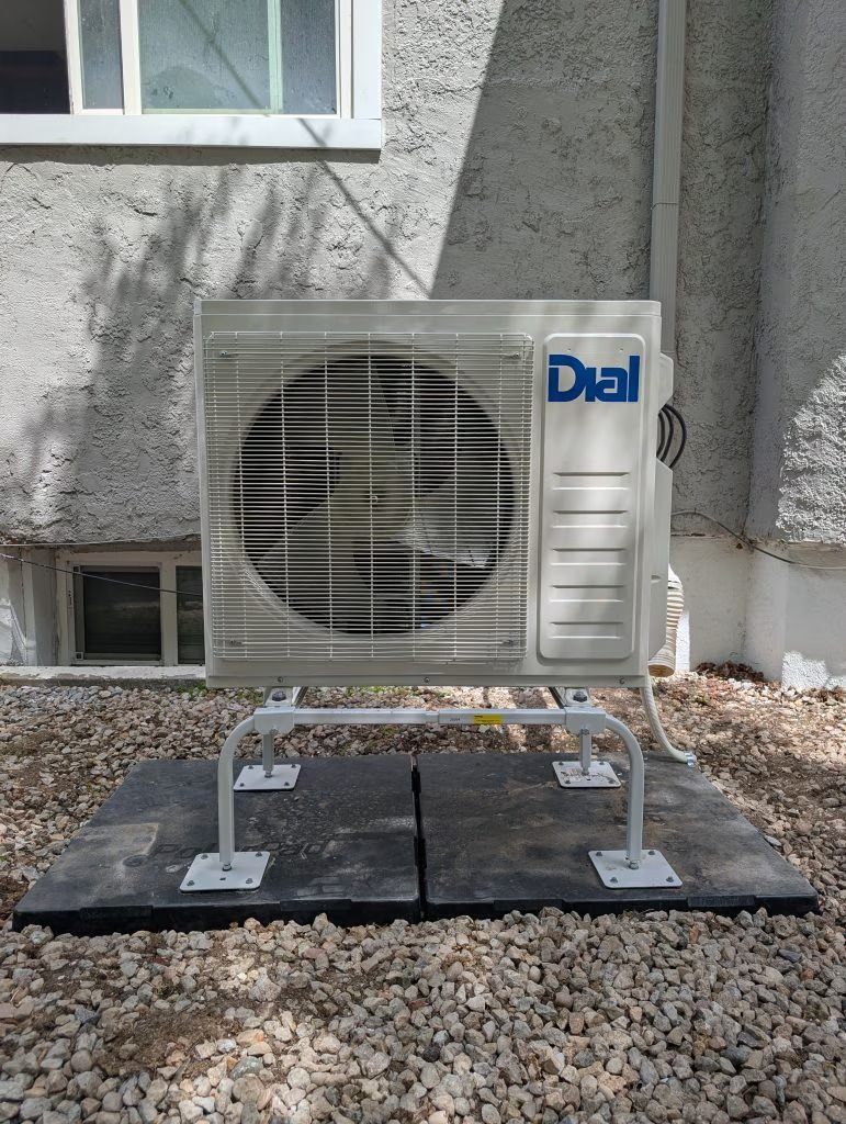 Outdoor DAI air-conditioning unit on a metal stand beside a building wall