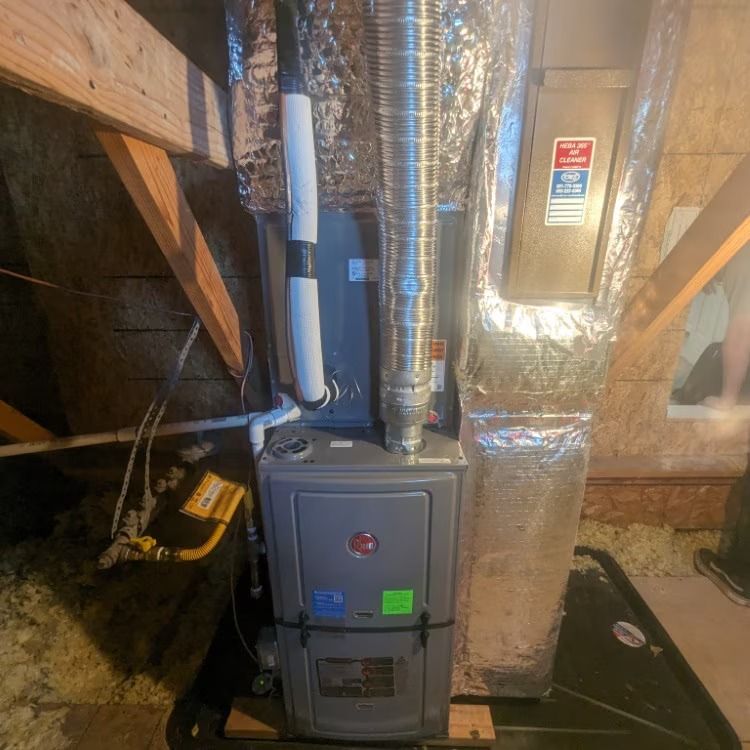 Basement furnace with silver ductwork and insulated pipes under exposed wooden beams.