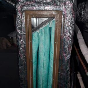 Foil-wrapped rectangular vent with turquoise fabric curtain panel in a dark interior