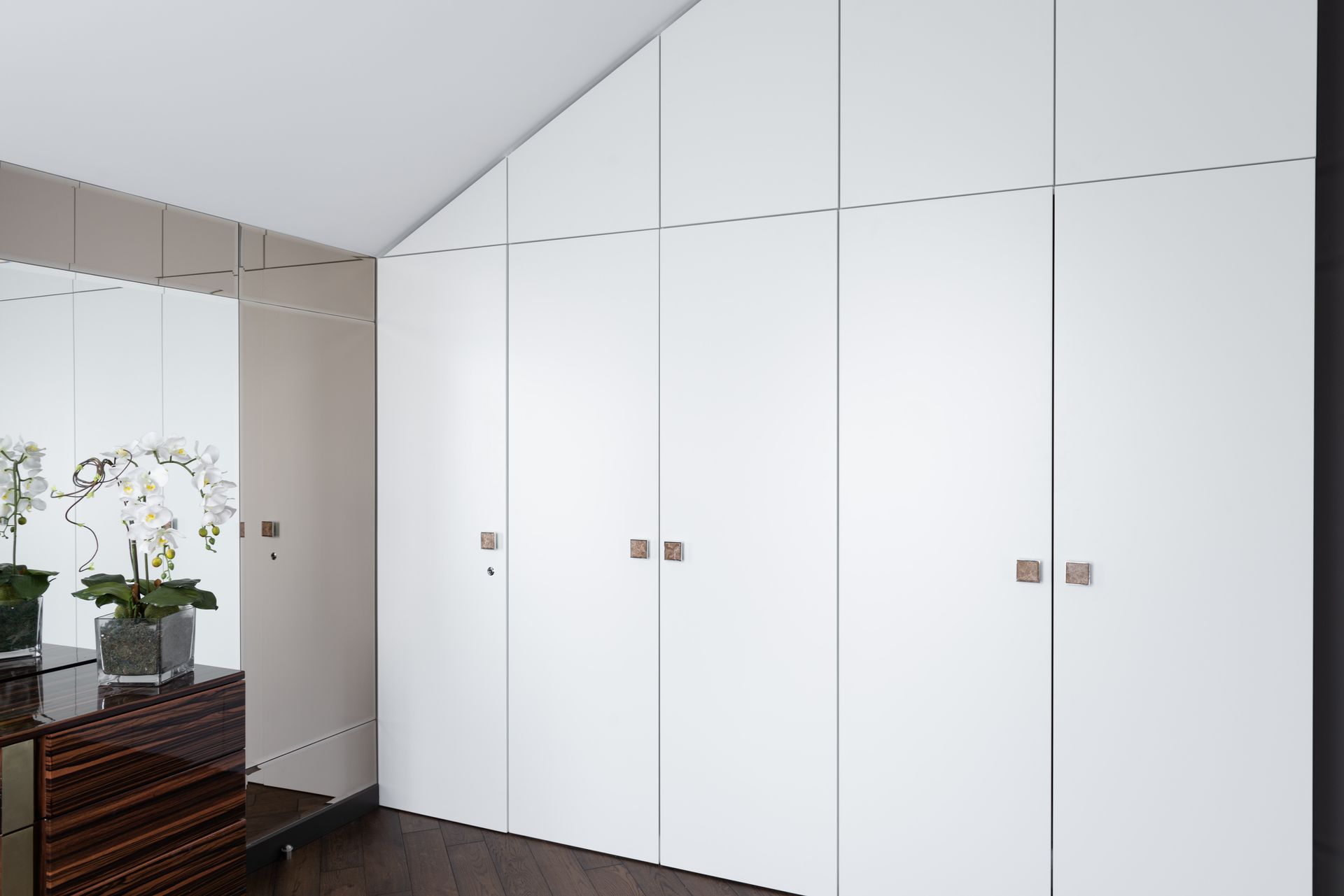 A room with a lot of white cabinets and a mirror.