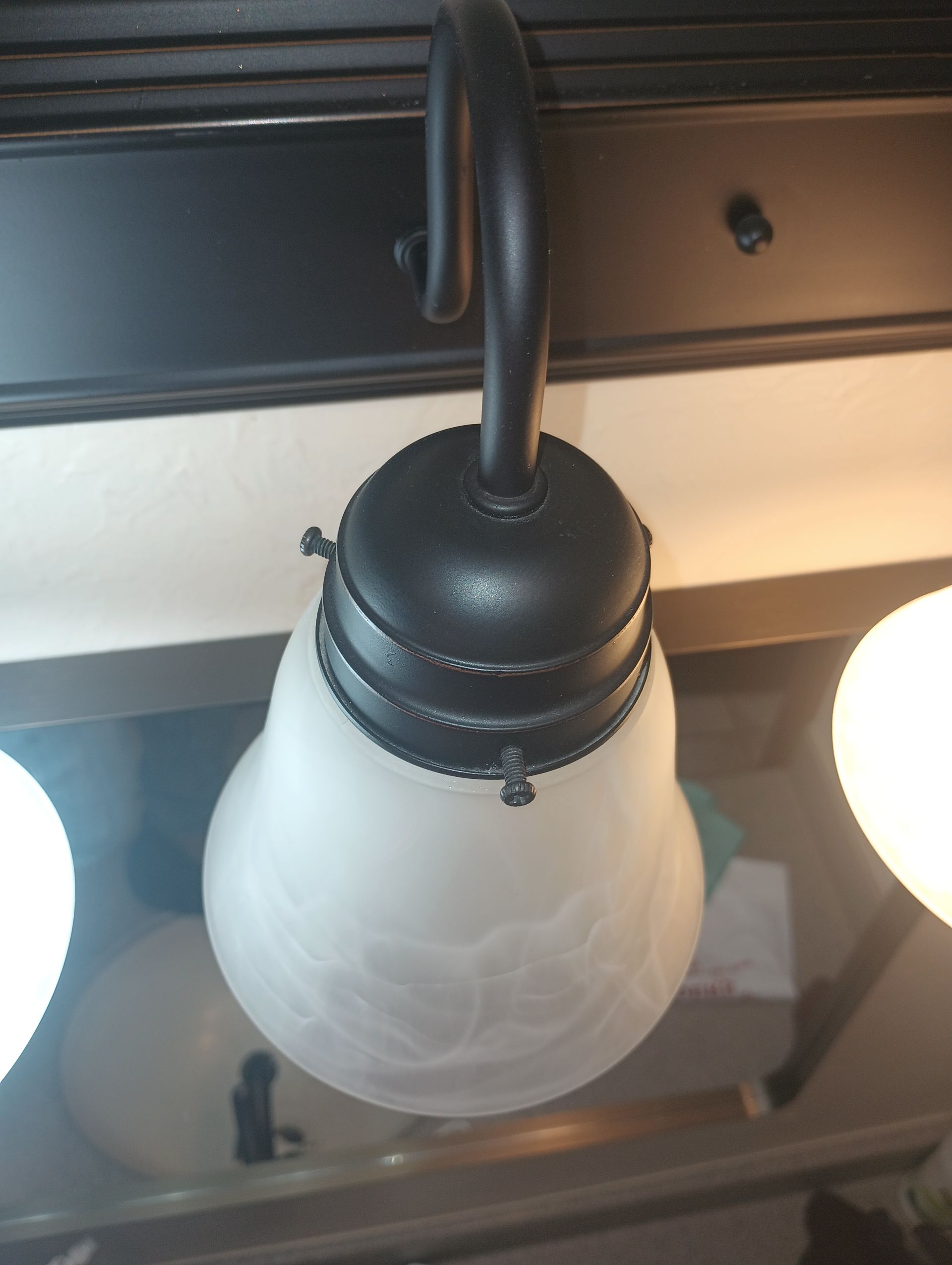 Ceiling-mounted black-and-white frosted glass light fixture with two lit bulbs on either side