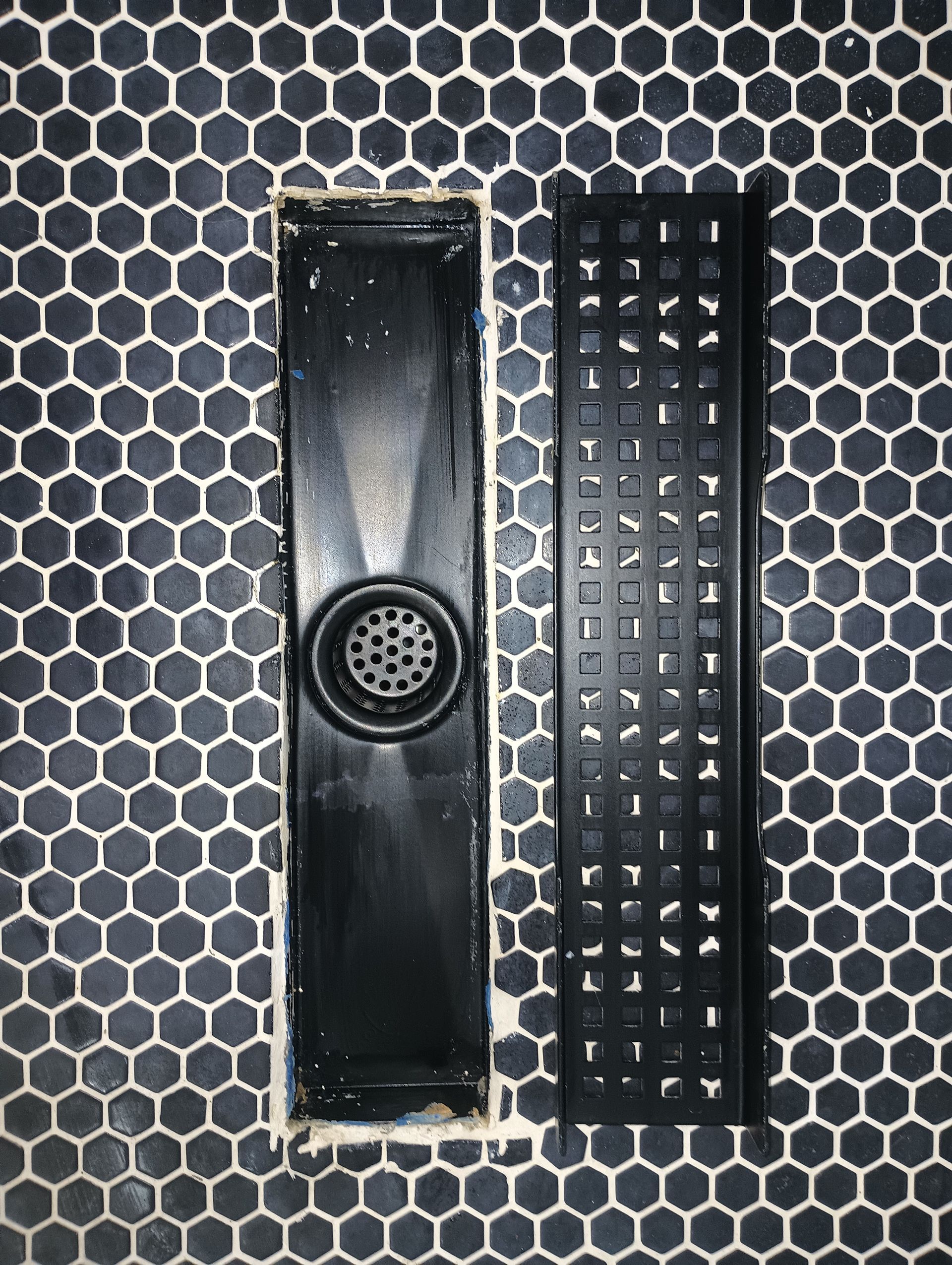 Black electronic device parts on a gray hexagon-patterned surface, including a long panel and a button grid.