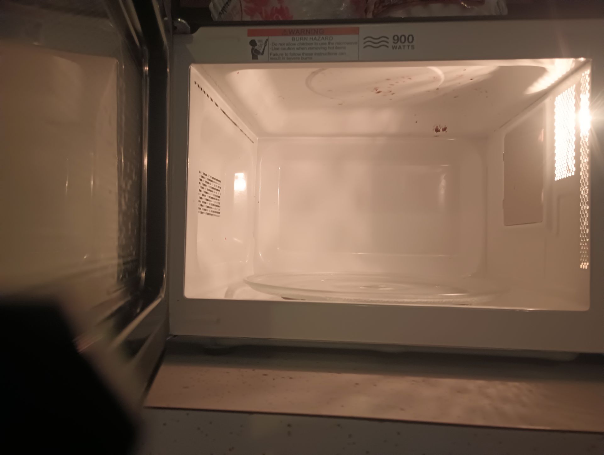 Open microwave with a white interior and glass turntable inside.