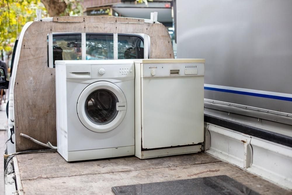 White washing machine and small fridge on a truck bed, ready for transport