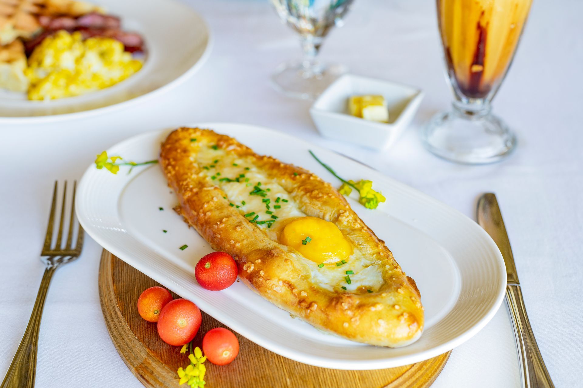 Grilled fish fillet with lemon and cherry tomatoes on a white plate at a dining table