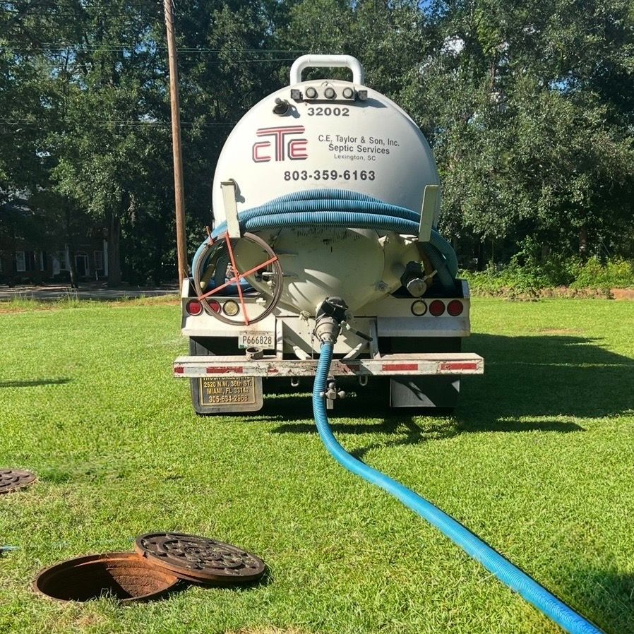 Person standing by a hose at the opening of a muddy pit or drain trench