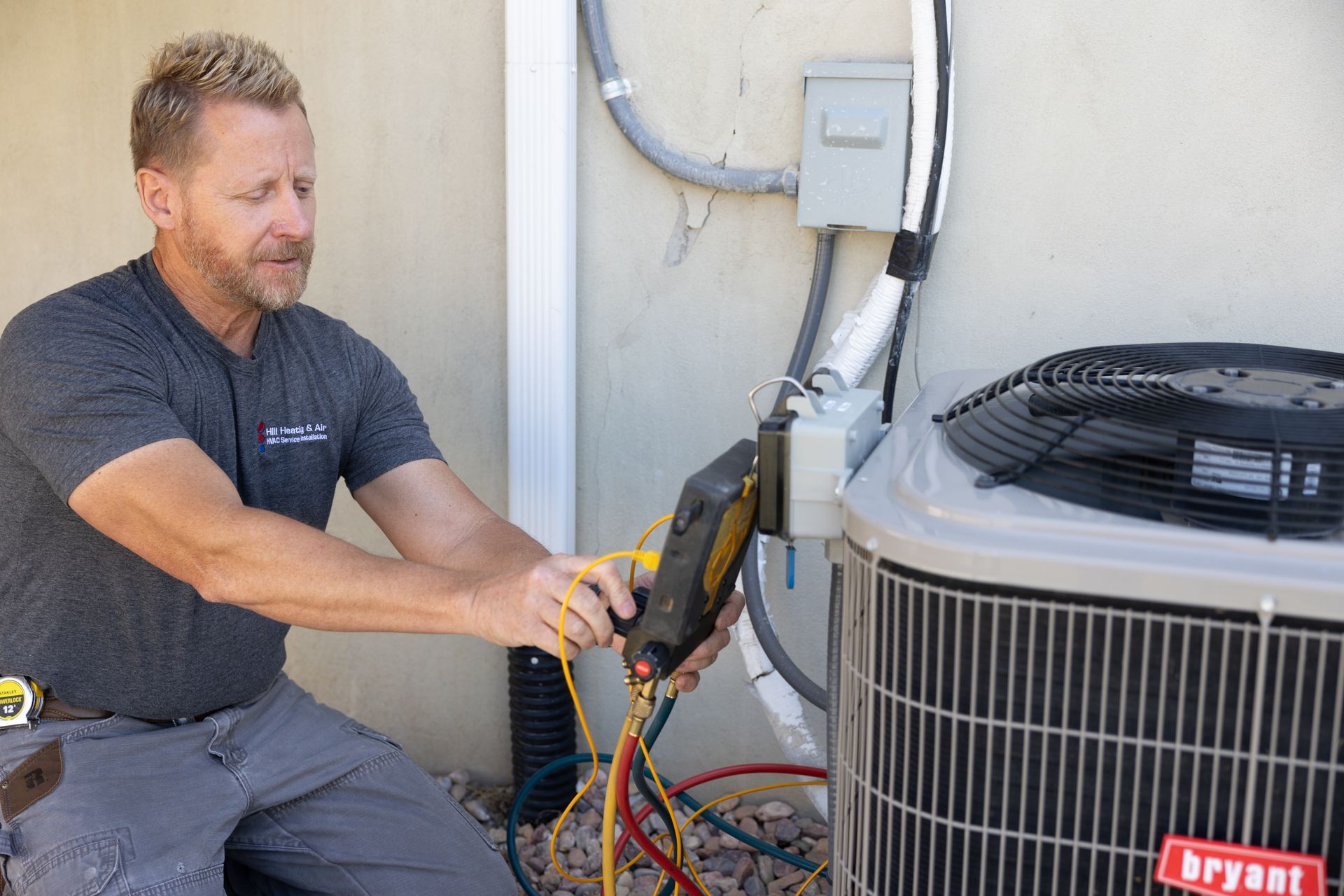 HVAC technician working on an air conditioning unit outside, using tools and gauges.