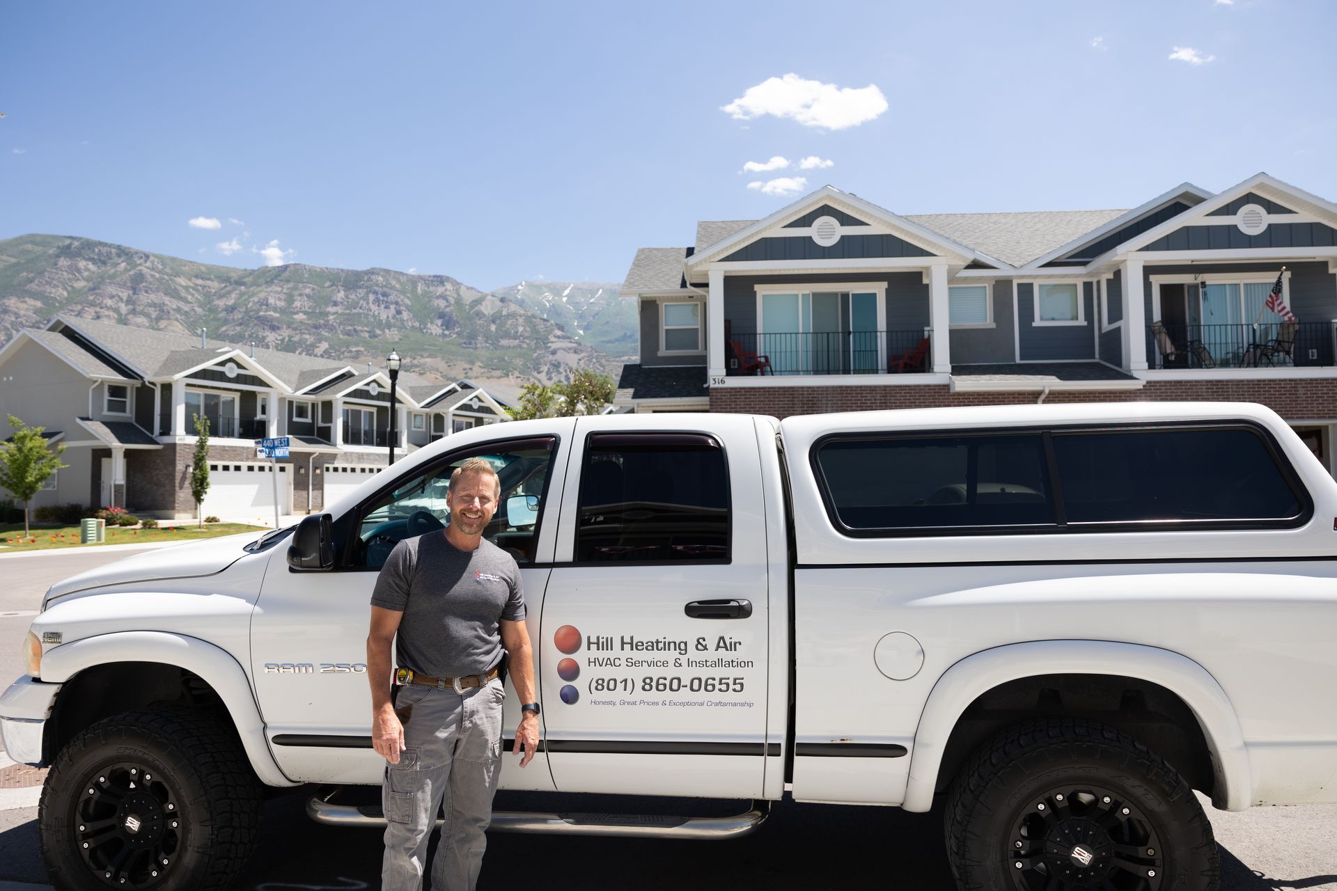A man is standing next to a white truck in front of a house. A man is standing next to a white truck in front of a house.