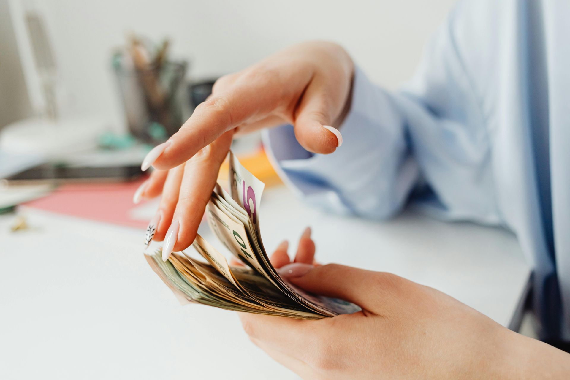 Hands holding and counting a stack of US dollar bills.