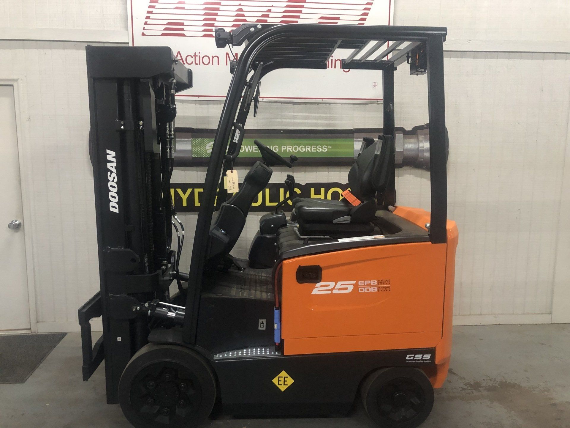 Orange and black forklift parked indoors against a wall