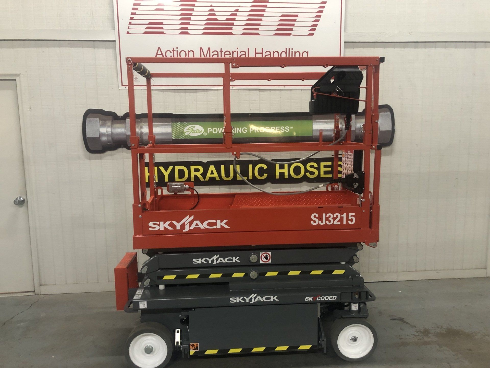 Red Skyjack SJ3215 scissor lift with “Hydraulic Hose” sign in an indoor warehouse