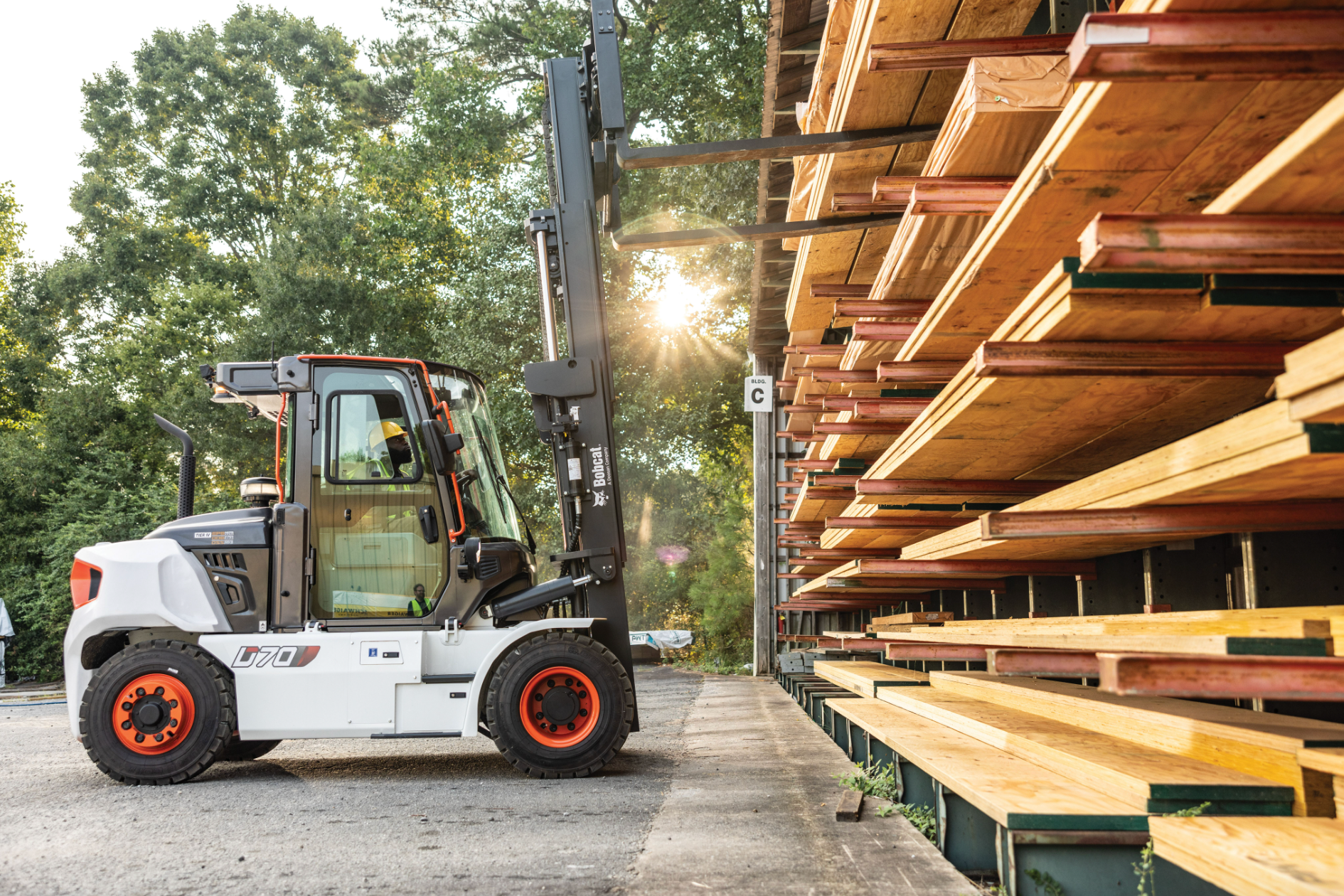 Forklift loading stacked lumber at an outdoor sawmill yard