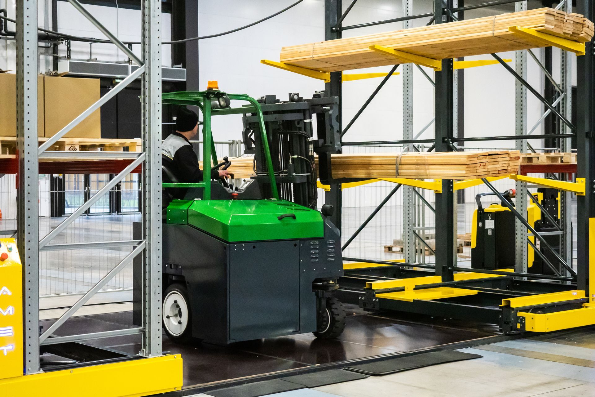 Forklift moving yellow pallets in an industrial warehouse with metal shelving and machinery