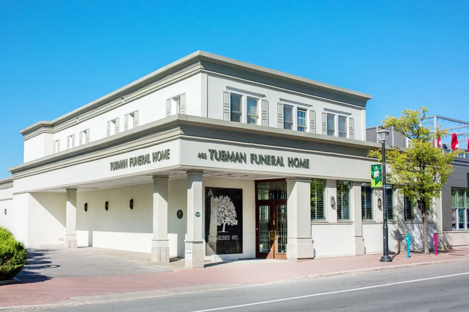 White corner building with green trim and sign reading “Tukerman Korean House” on a sunny street corner