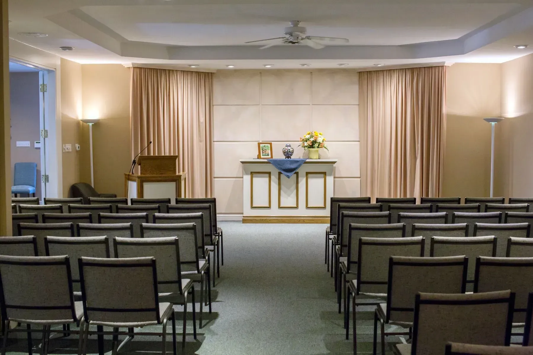 Small chapel or ceremony room with rows of chairs facing a decorated altar and curtains.