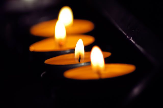 Three lit candles glowing in the dark