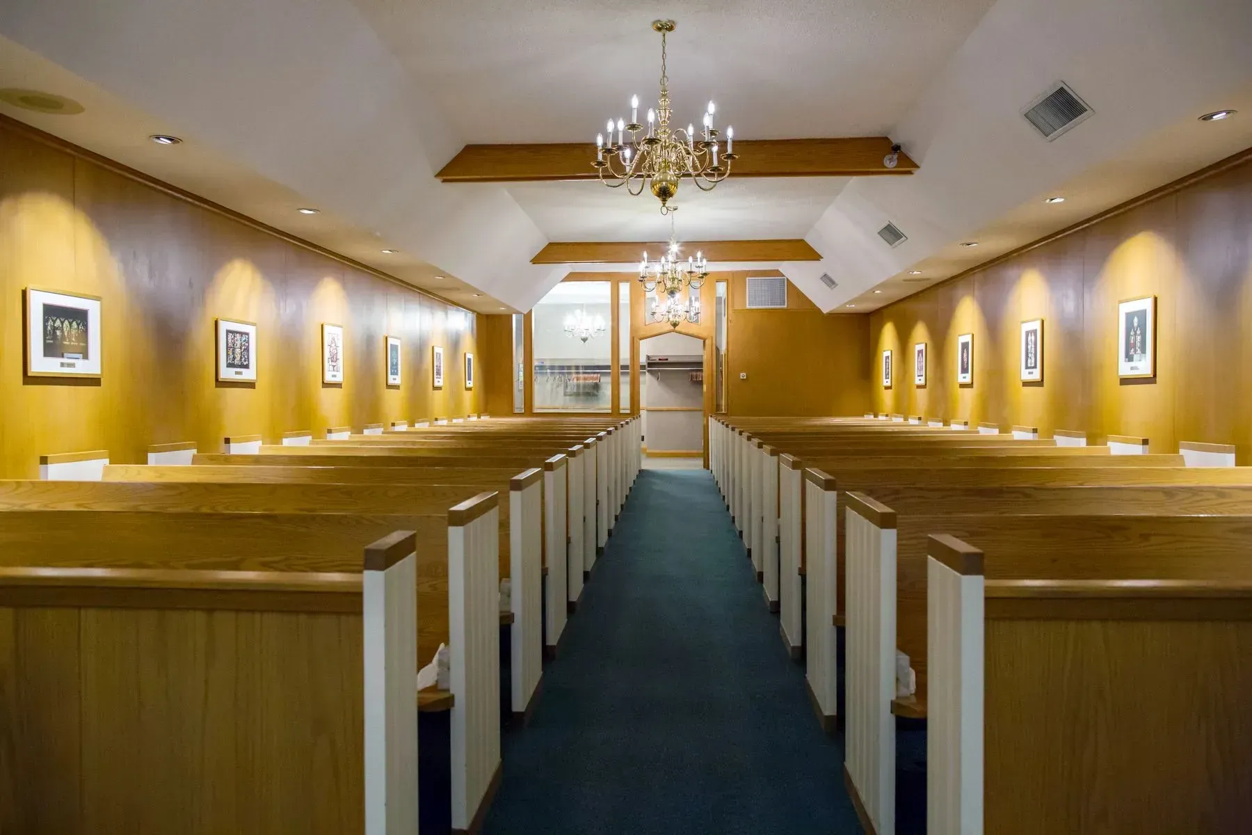 Empty church interior with wooden pews, chandelier, and a central aisle leading to the altar