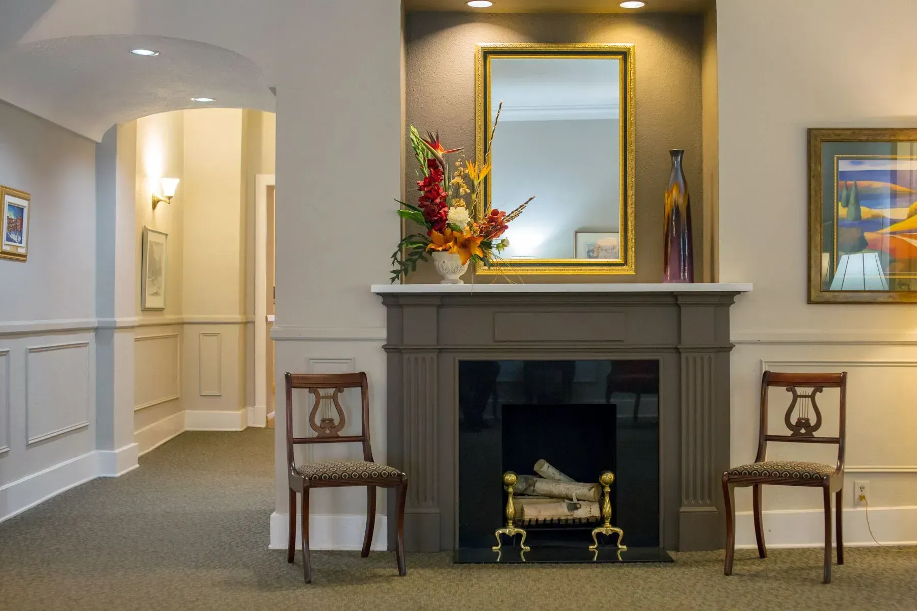 Elegant hotel lobby with fireplace, mirror, flowers, and two chairs