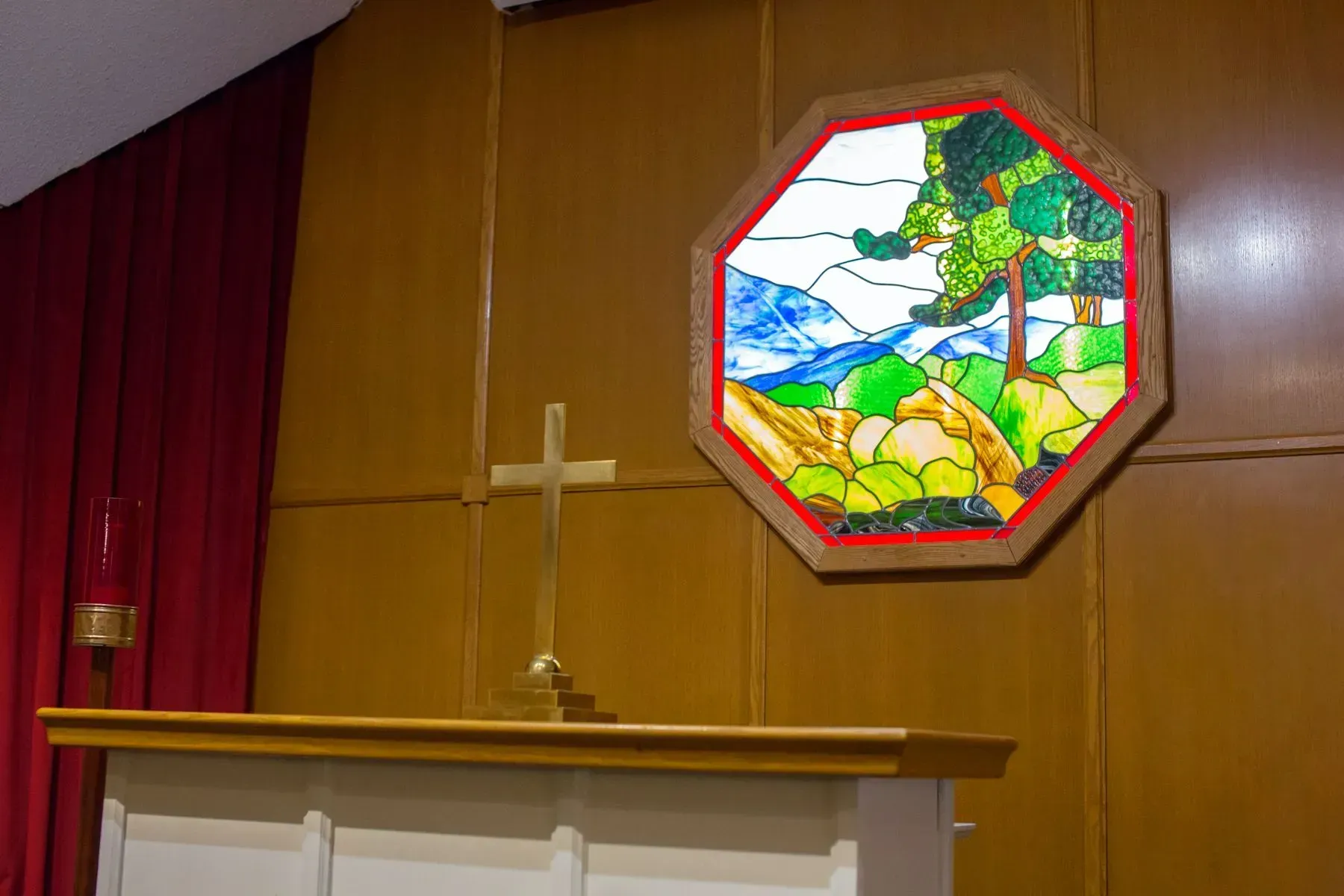 Church altar with wooden cross and stained-glass window above it