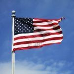 American flag waving on a pole against a blue sky