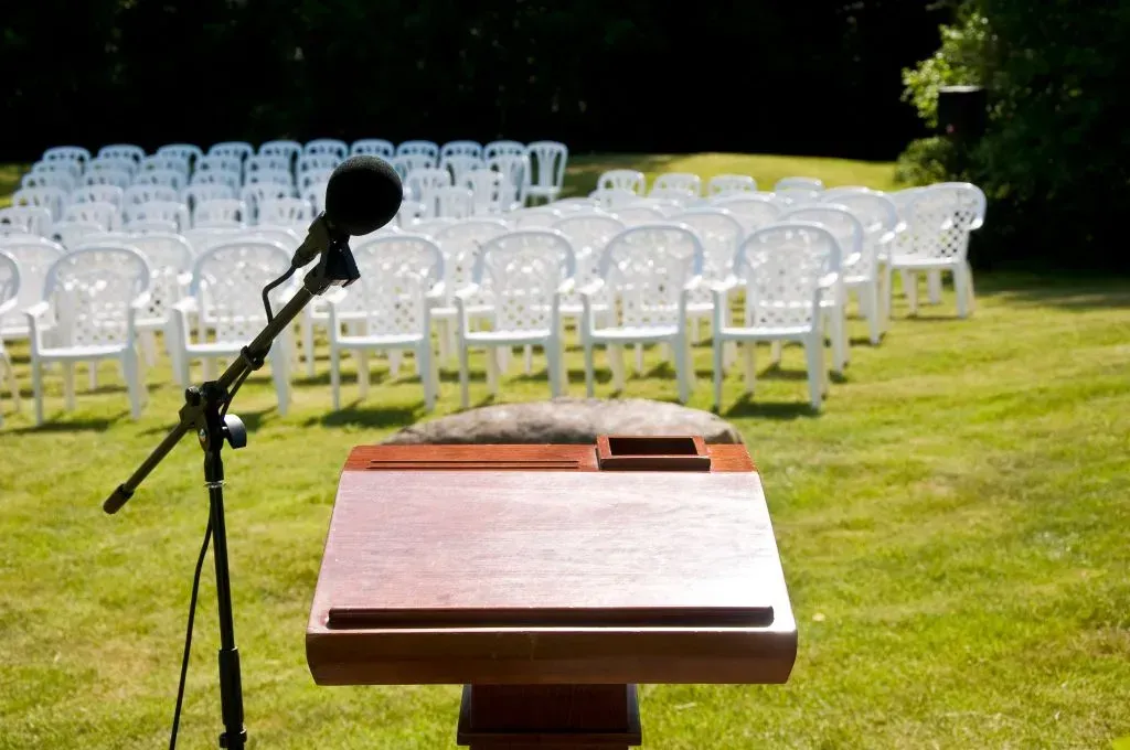 A group of people are standing around a urn at a funeral.