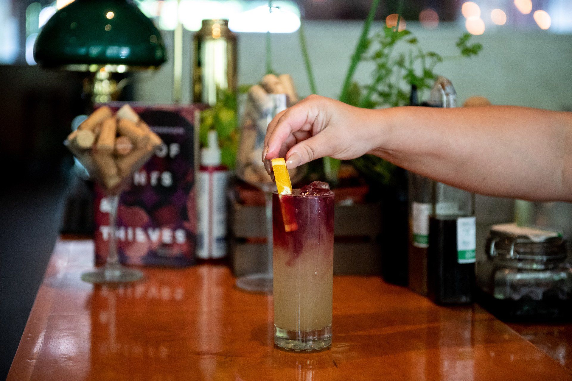 A person is pouring a drink into a glass on a bar.