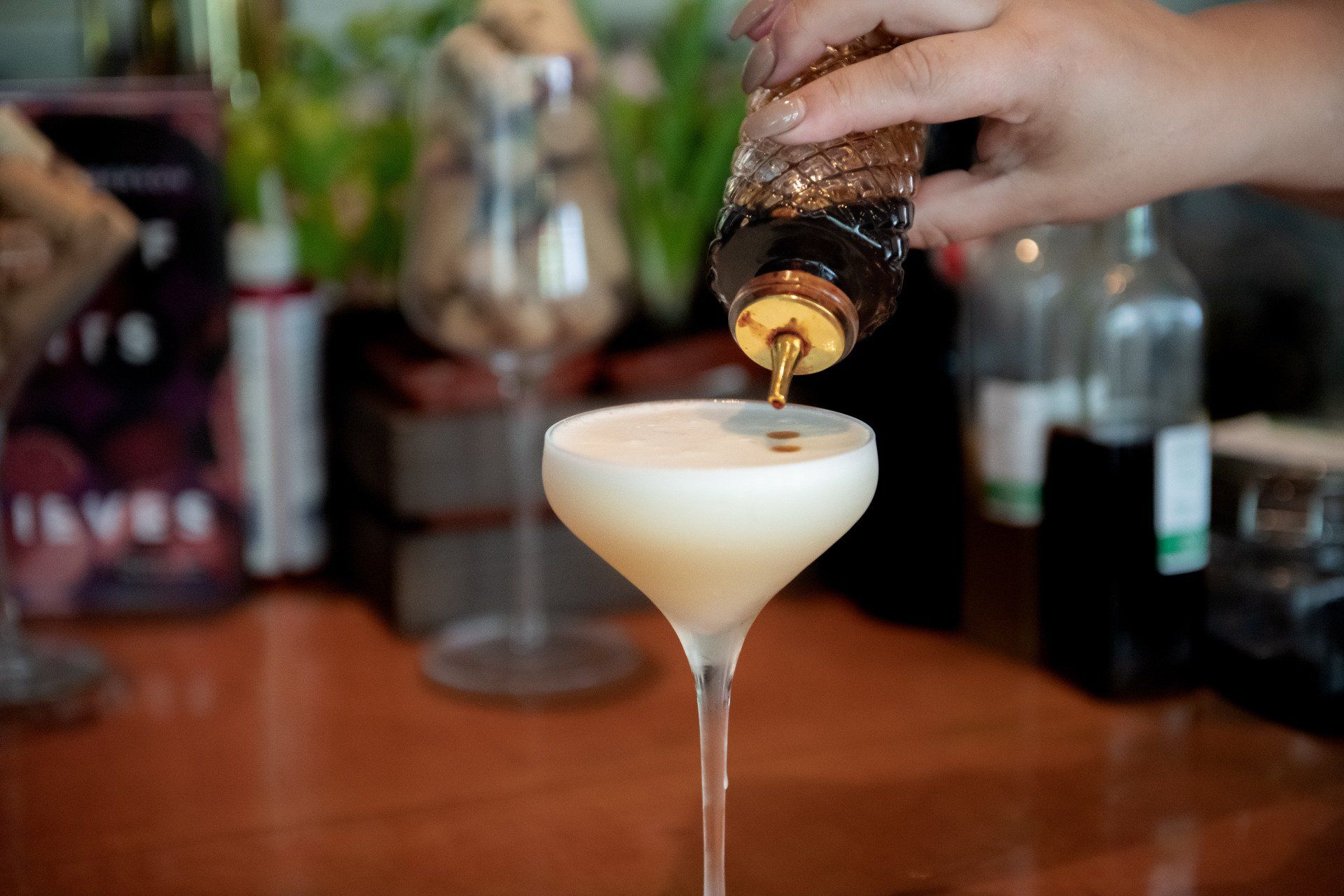 A person is pouring a drink into a martini glass.