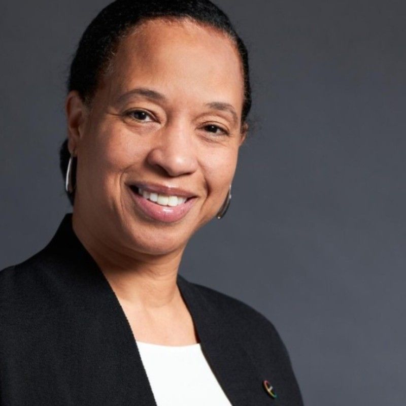 A woman wearing a black jacket and white shirt smiles for the camera