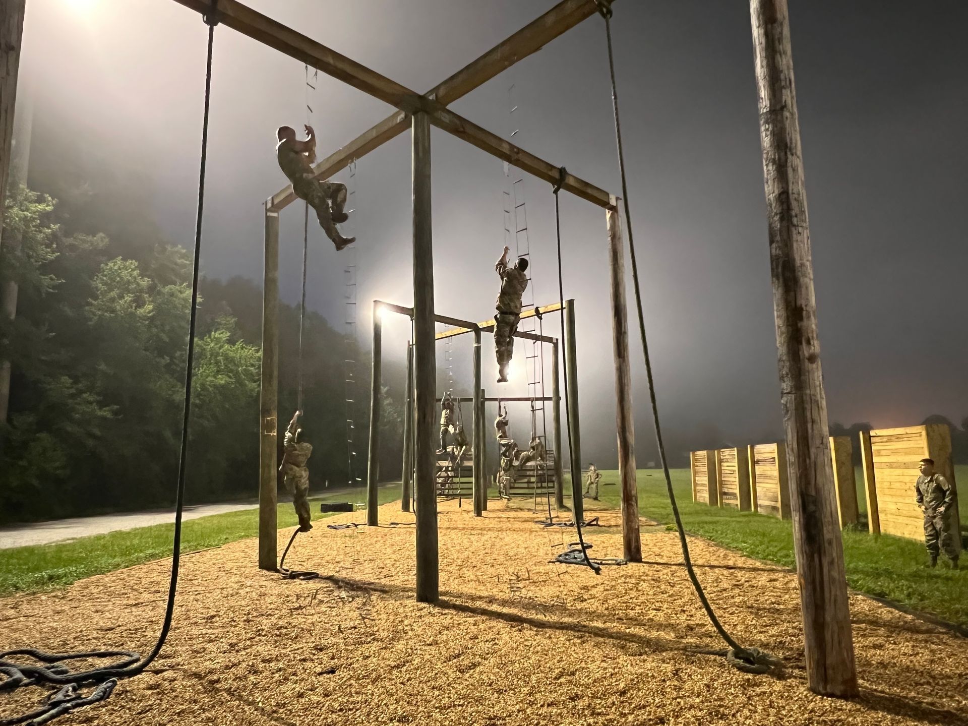 A group of people are climbing ropes on a playground at night. A group of people are climbing ropes on a playground at night.