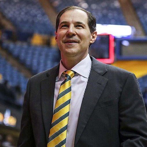 A man in a suit and tie is standing in a stadium. A man in a suit and tie is standing in a stadium.