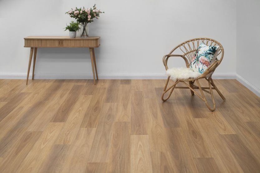 A Wicker Chair Is Sitting On A Wooden Floor Next To A Wooden Table — Flooring Suppliers in Port Macquarie, NSW