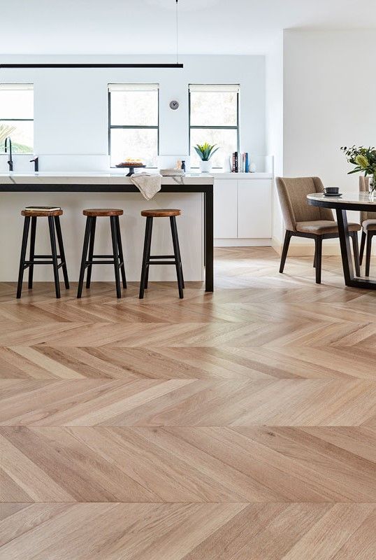 A Kitchen with A Island in the Middle with Three Chairs on a Wooden Floor — Flooring Suppliers in Port Macquarie, NSW