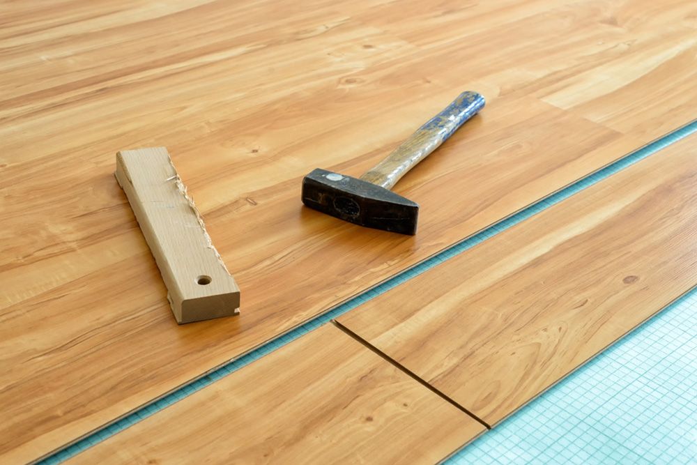 Hammer and a piece of wood in the floor — Floor Coverings in Taree, NSW