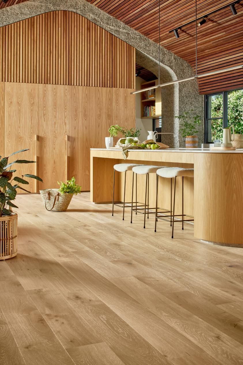 A Kitchen With A Wooden Floor, Stools, And A Large Island — Flooring Suppliers in Port Macquarie, NSW