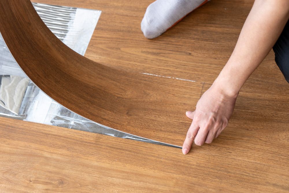 Man carefully installing vinyl — Floor Coverings in Harrington, NSW