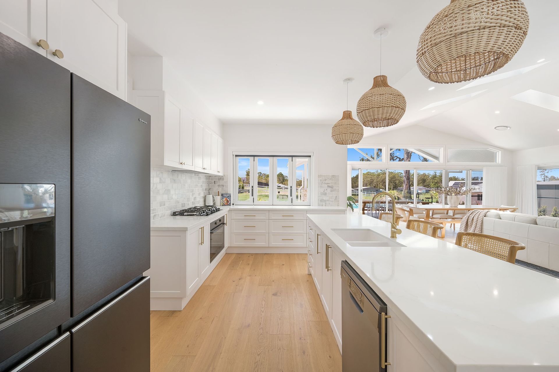 Bright modern kitchen with white cabinets, wood floors, island, and woven pendant lights