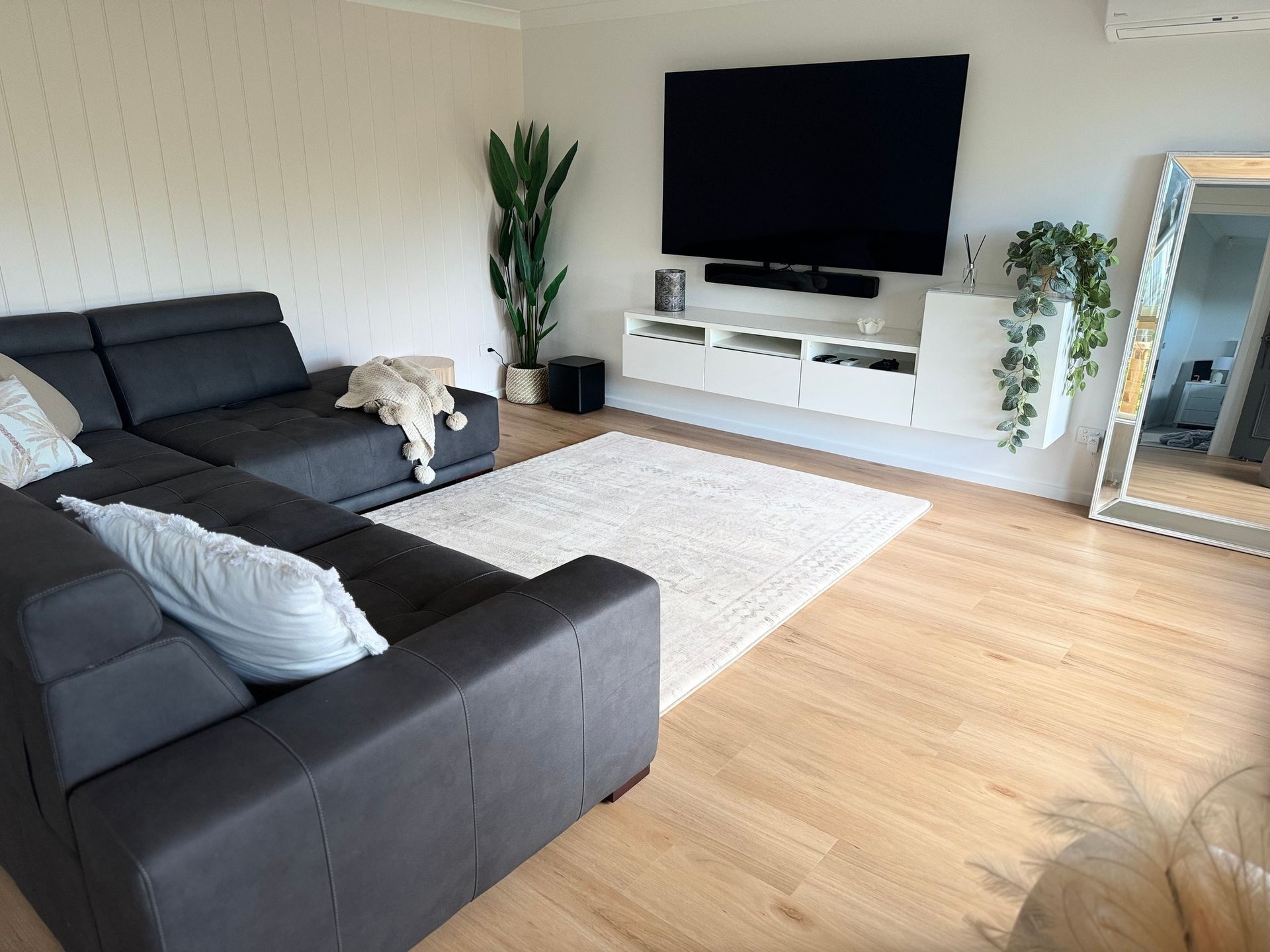 A spacious, light-filled kitchen with light wood floors, a white center island, and large windows overlooking water.
