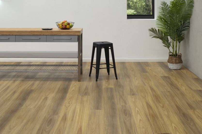 A Wooden Floor With A Black Stool and a Plant on Right Side — Flooring Suppliers in Port Macquarie, NSW