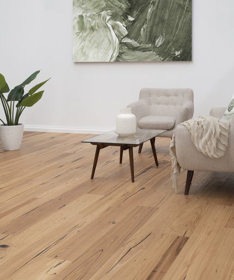 A Living Room With Hardwood Floors And A Painting On The Wall — Flooring Suppliers in Port Macquarie, NSW