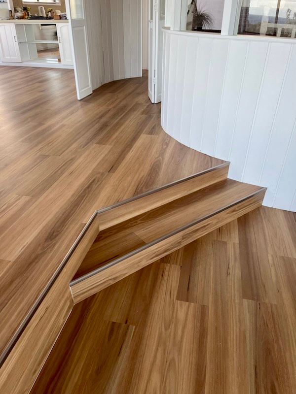 A Wooden Floor With Stairs Leading Up To It In A Room — Flooring Suppliers in Port Macquarie, NSW