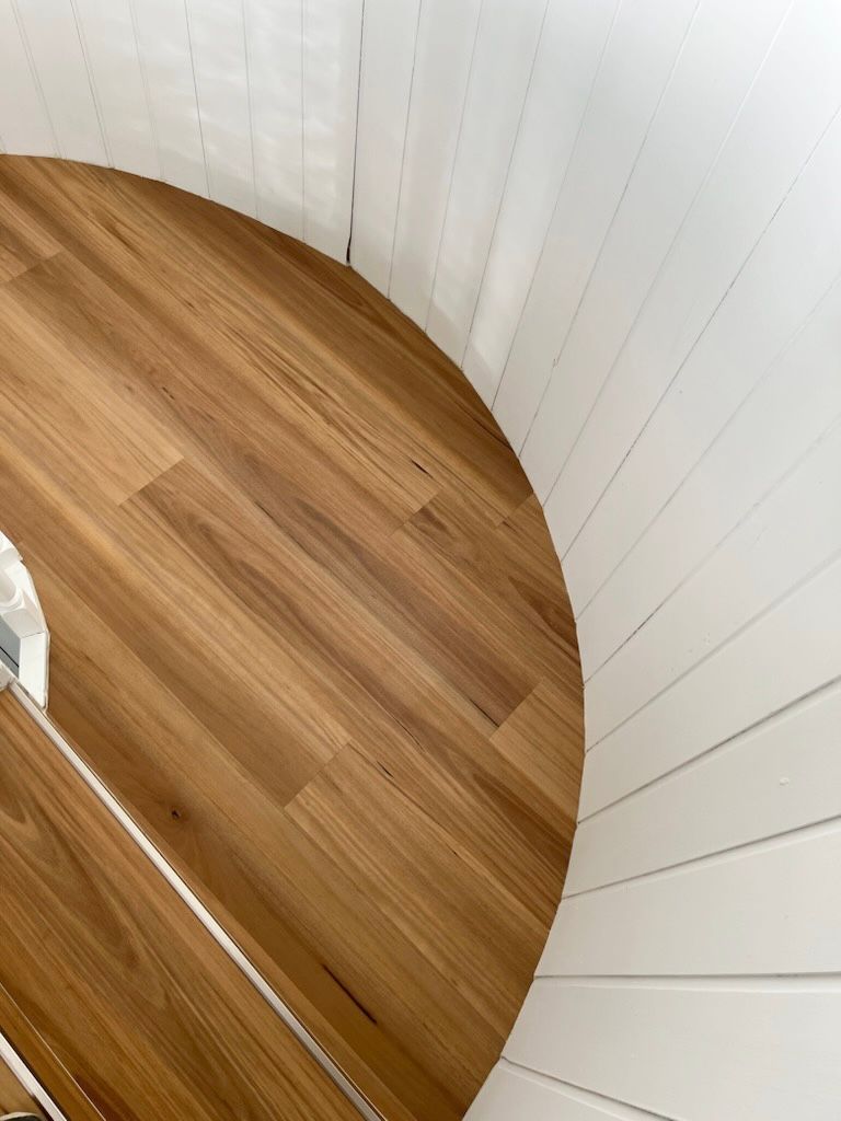 A Spiral Staircase With A Wooden Floor And White Walls — Flooring Suppliers in Port Macquarie, NSW