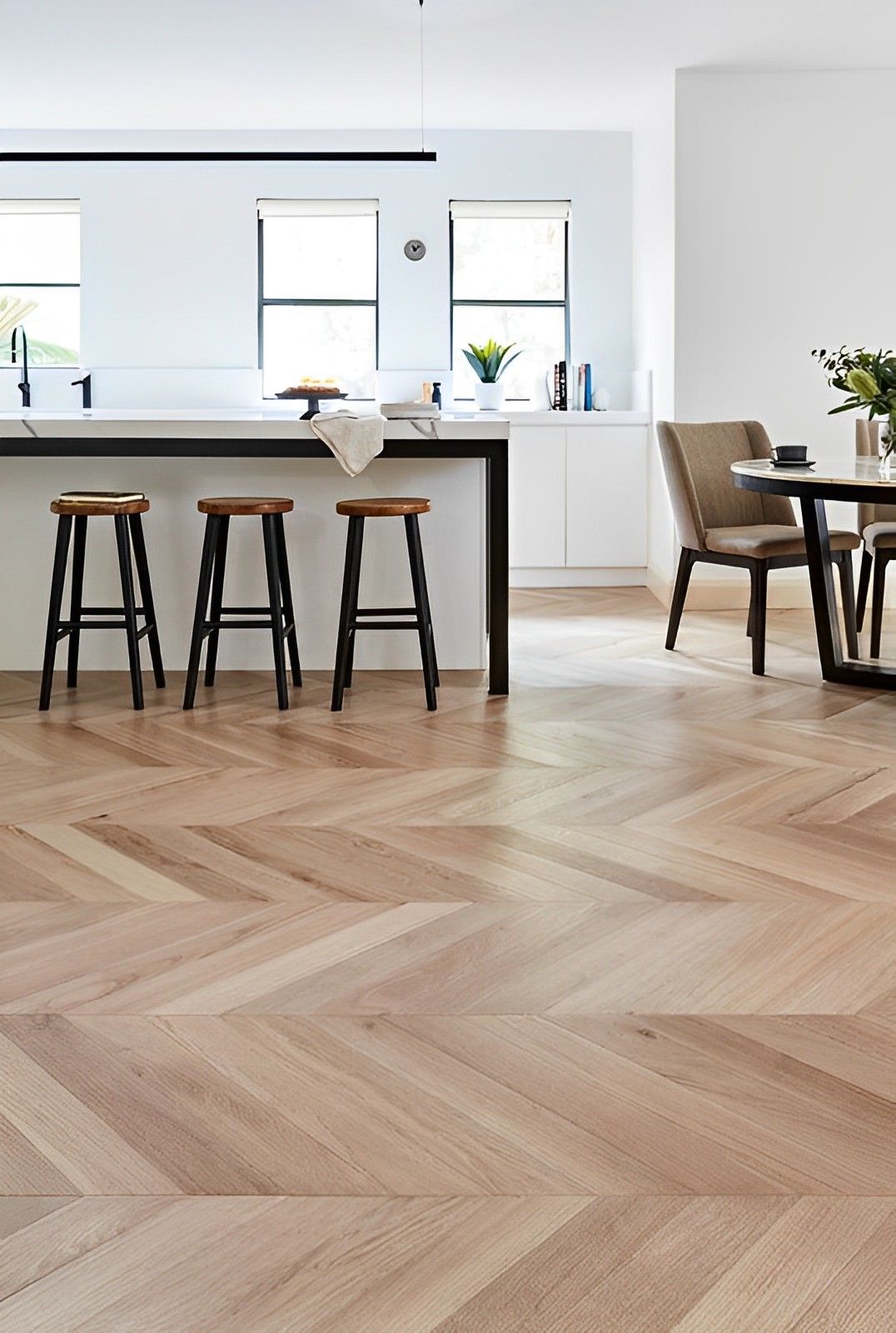 A kitchen with a wooden floor , stools , a table and chairs.