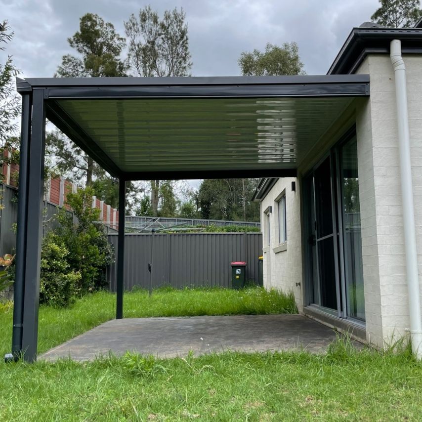 A Dark Gray Pergola Attached to a White House — Narellan Home Improvement Centre In Wollongong, NSW