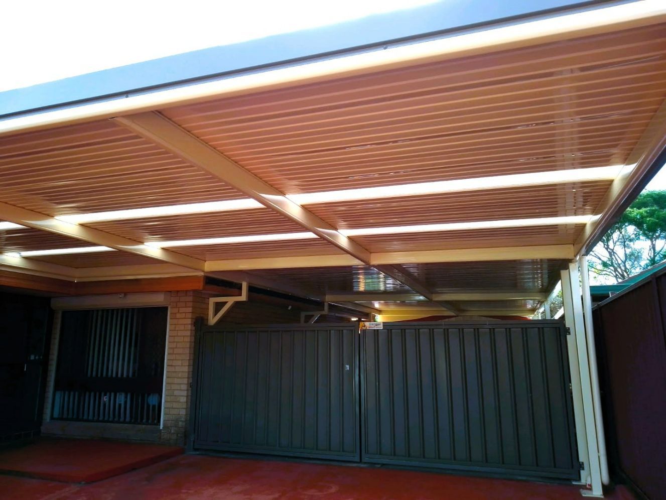 A Brown Metal Pergola Over a Driveway With Dark Brown Gates — Narellan Home Improvement Centre In Wollongong, NSW