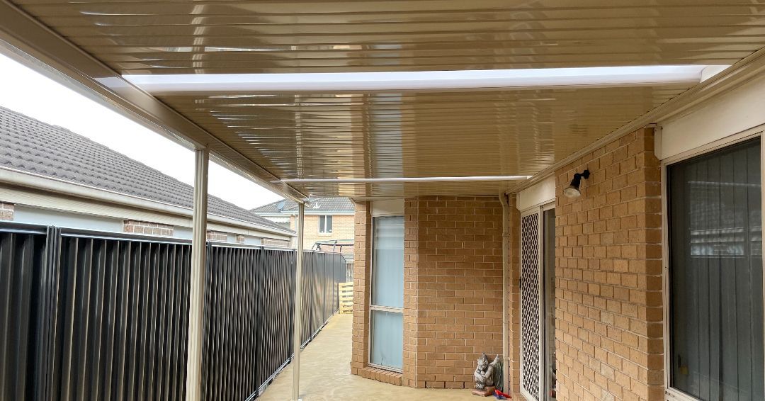 Covered Patio With Beige Roof, Black Fence, and House Window — Narellan Home Improvement Centre In Queanbeyan, NSW
