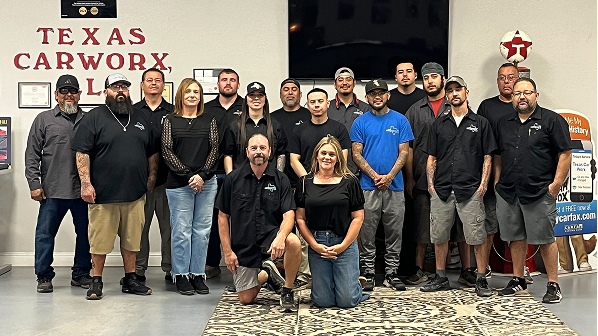 Group of people posing in a showroom with a Texas Carworks sign on the wall | Texas Carworx