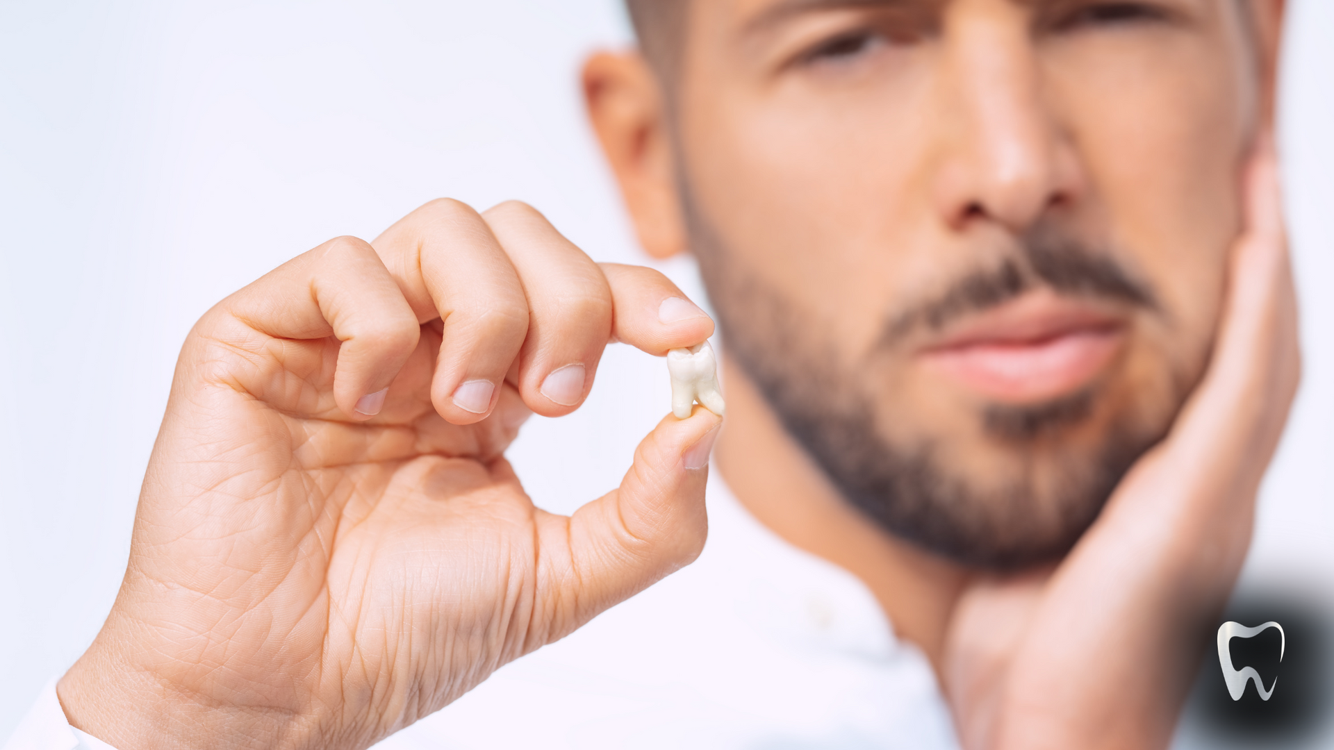 A man with a beard is holding a tooth in his hand.