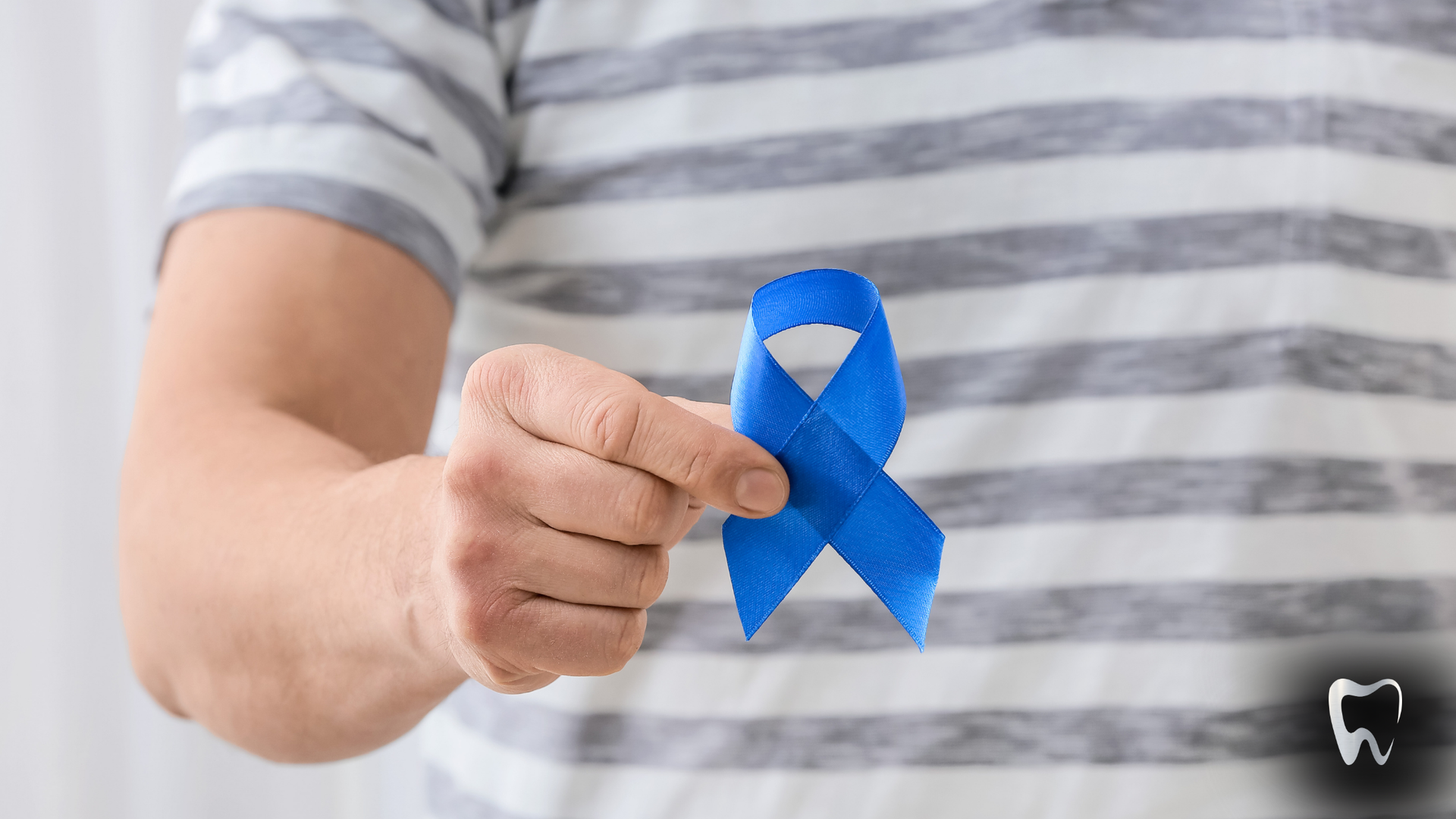 A man is holding a blue ribbon in his hand.